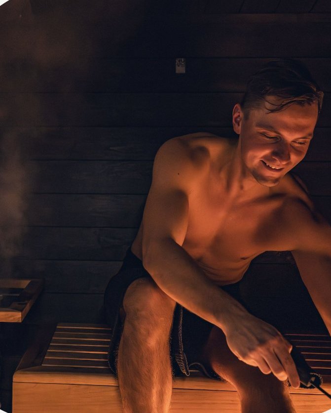 Guest throwing löyly in a dark wooden sauna